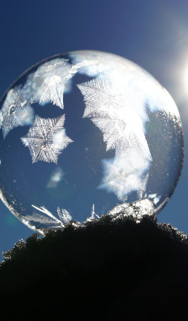 Мыльный пузырь в лучах солнца на снегу