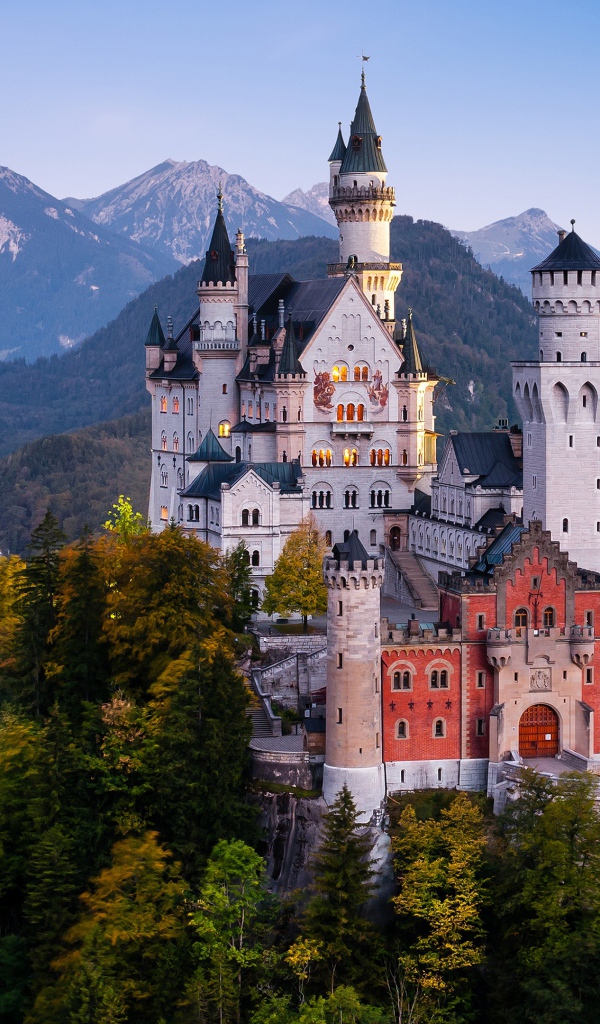 Neuschwanstein Castle in a forest thicket against a backdrop of mountains, Germany