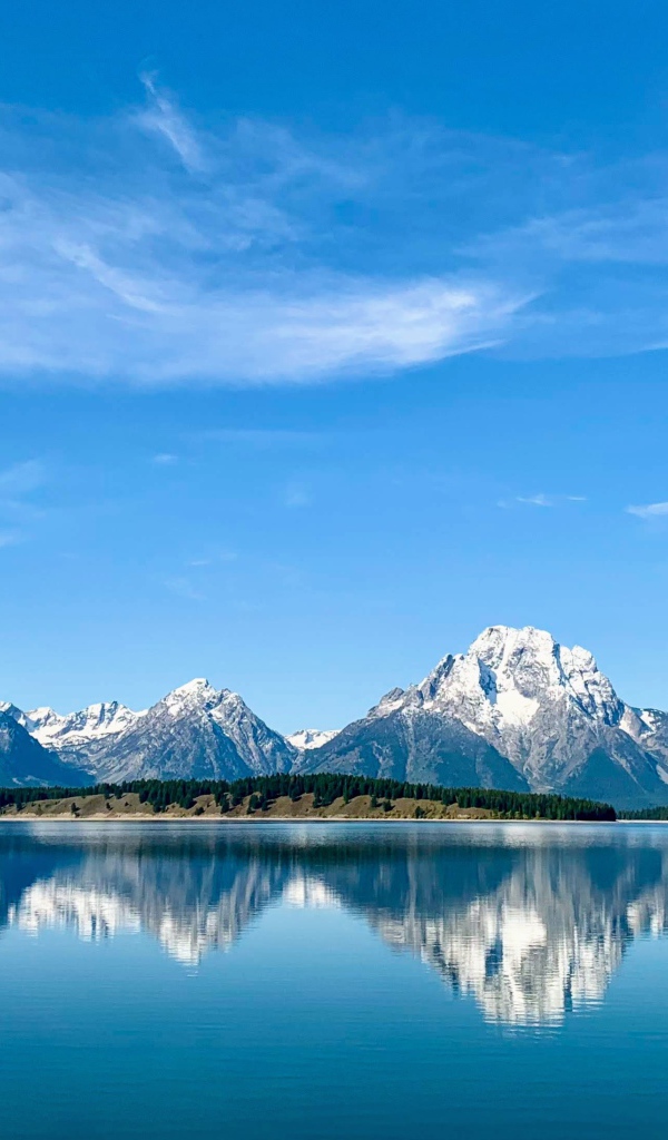 Вид на заснеженные горы под голубым небом у озера, Национальный парк Гранд Титон, Вайоминг. США