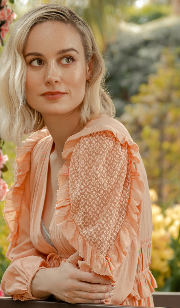 Актриса Бри Ларсон сидит у кустов с розовыми цветами