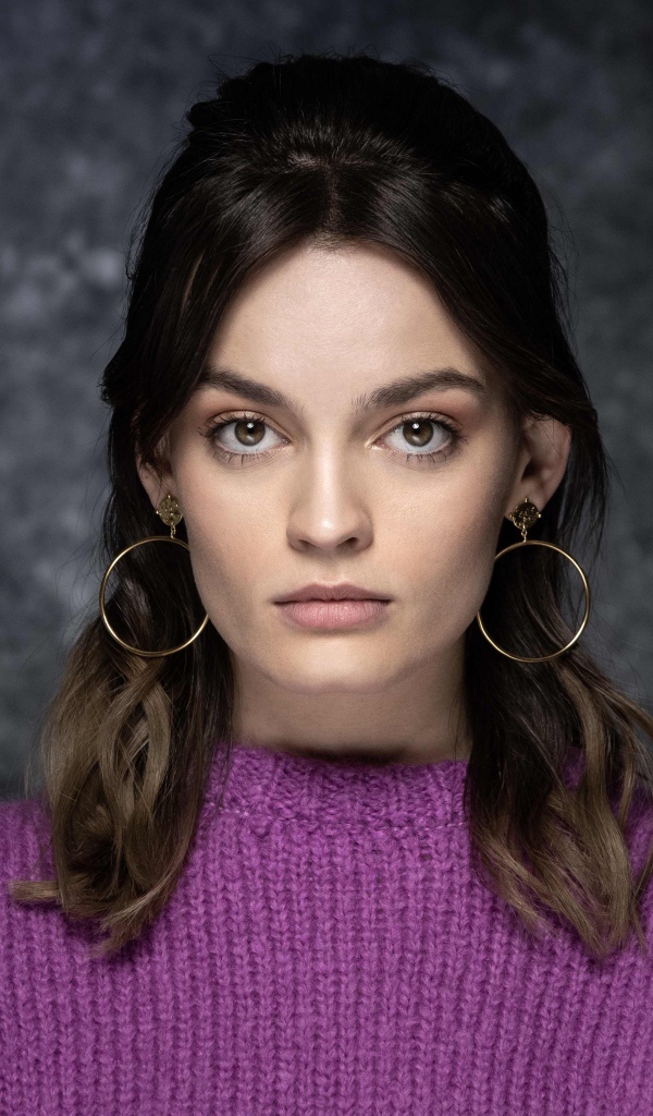 Актриса Эмма Маккей в сиреневом свитере на сером фоне