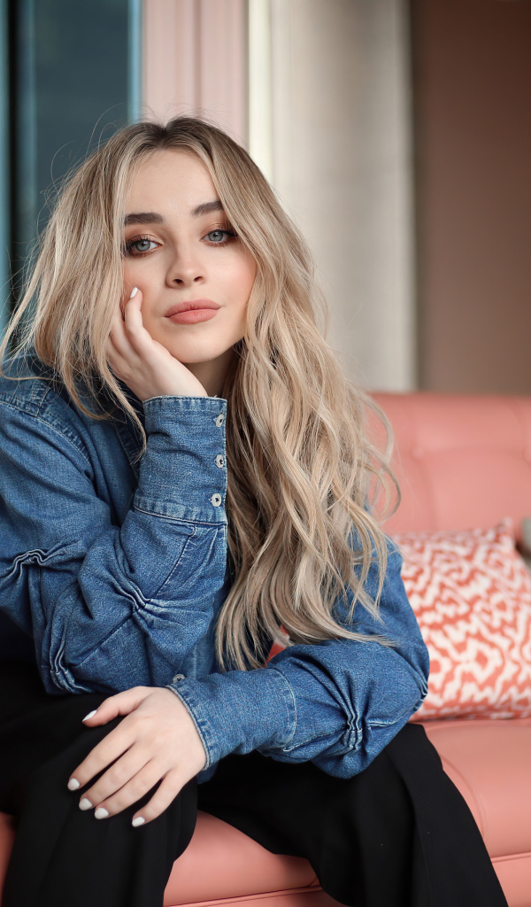 Актриса Сабрина Карпентер сидит на диване в комнате