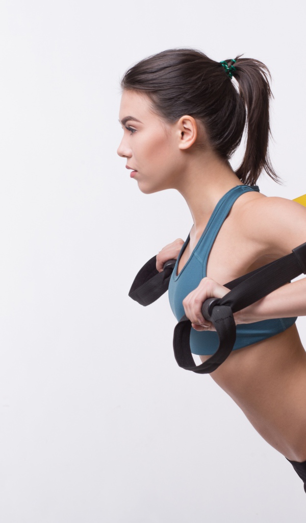 Спортивная девушка занимается в спортзале на белом фоне 