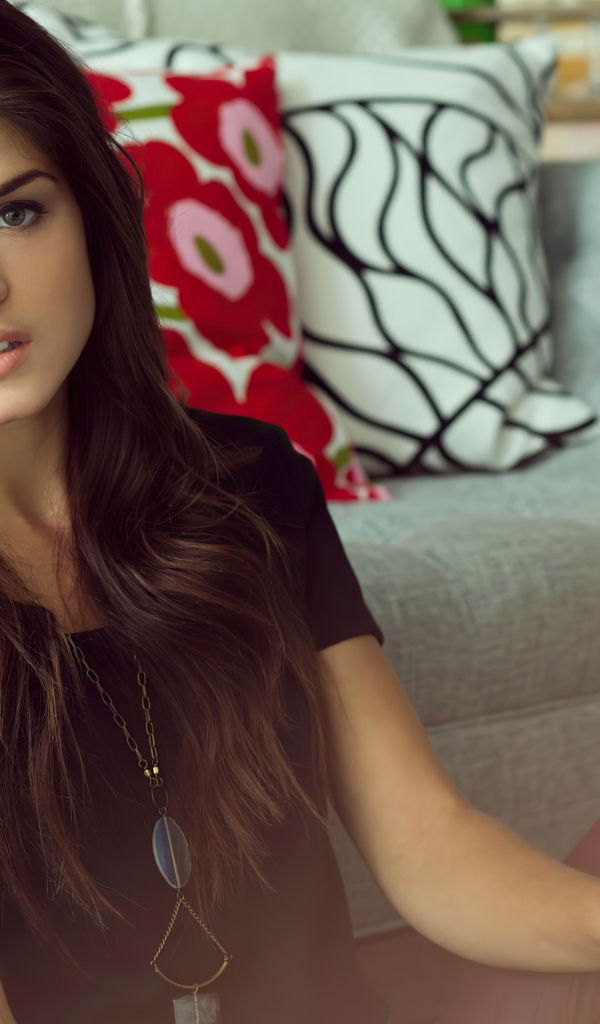 Красивая канадская актриса Мария Авгеропулос сидит у дивана