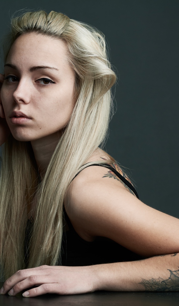 Beautiful blonde with tattoos on her body on a gray background