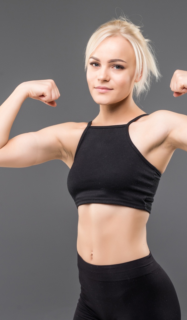 Красивая стройная спортивная девушка показывает мускулы