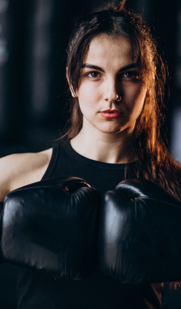 Девушка боксер с черными перчатками на руках 