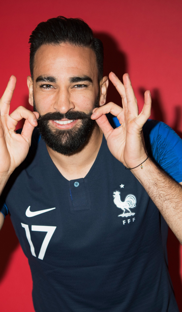 Французский футболист Адиль Рами на красном фоне