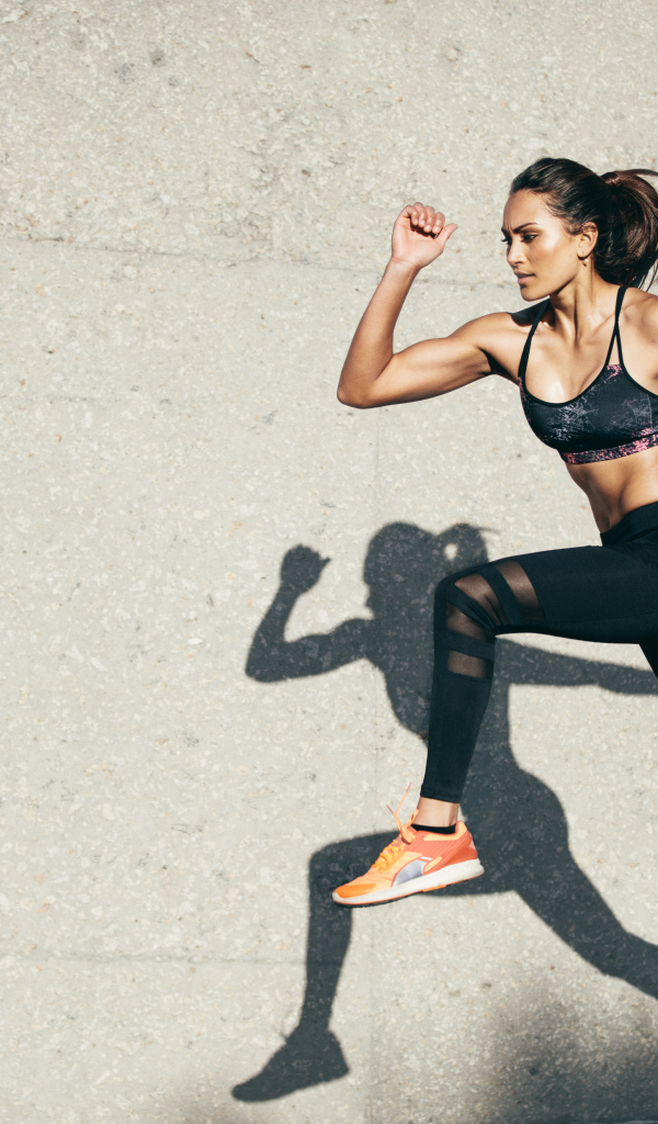 Девушка спортсменка бежит на стадионе 