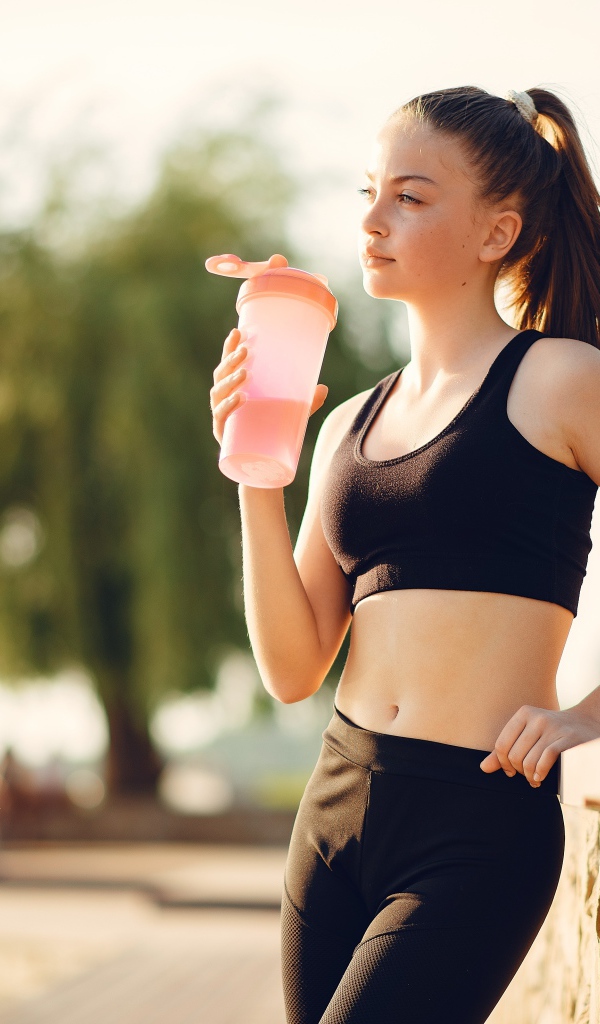 Девушка в черном спортивной форме с водой 