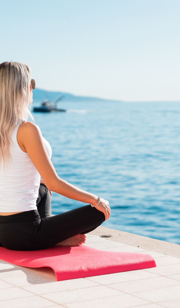 Девушка медитирует на берегу моря 