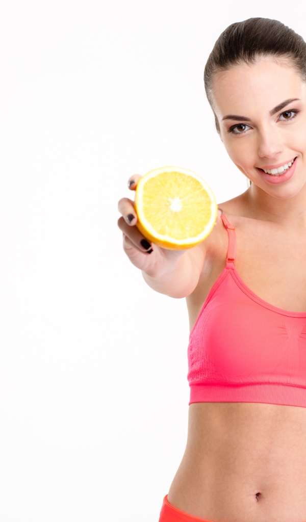 Девушка со стаканом сока и апельсином на белом фоне