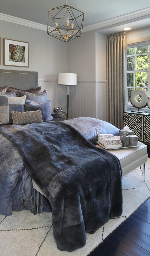 Большая кровать с мягким серым покрывалом в спальне 