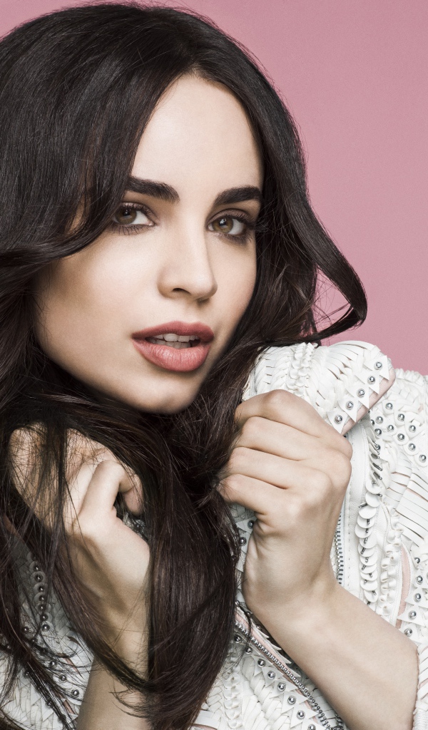 Длинноволосая актриса София Карсон на розовом фоне