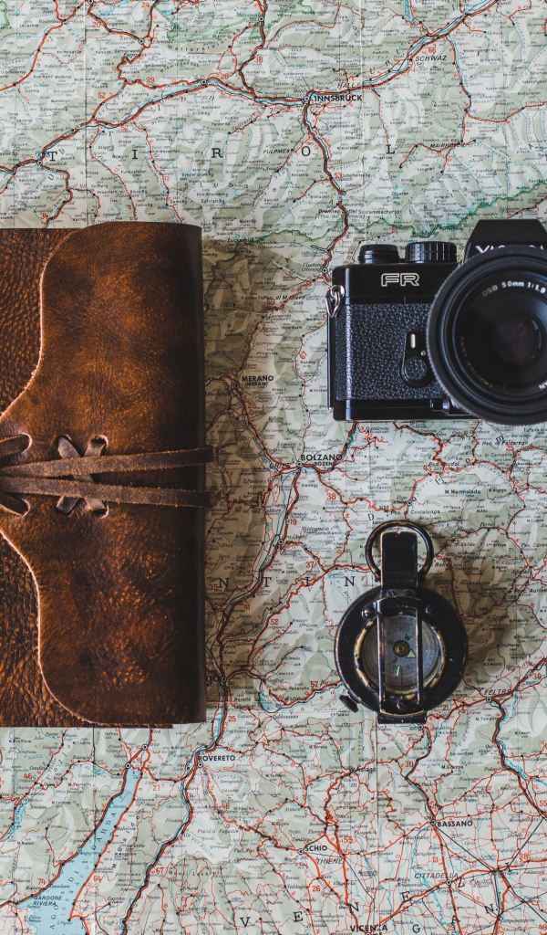 Старый фотоаппарат, компас, часы, блокнот и карта на столе