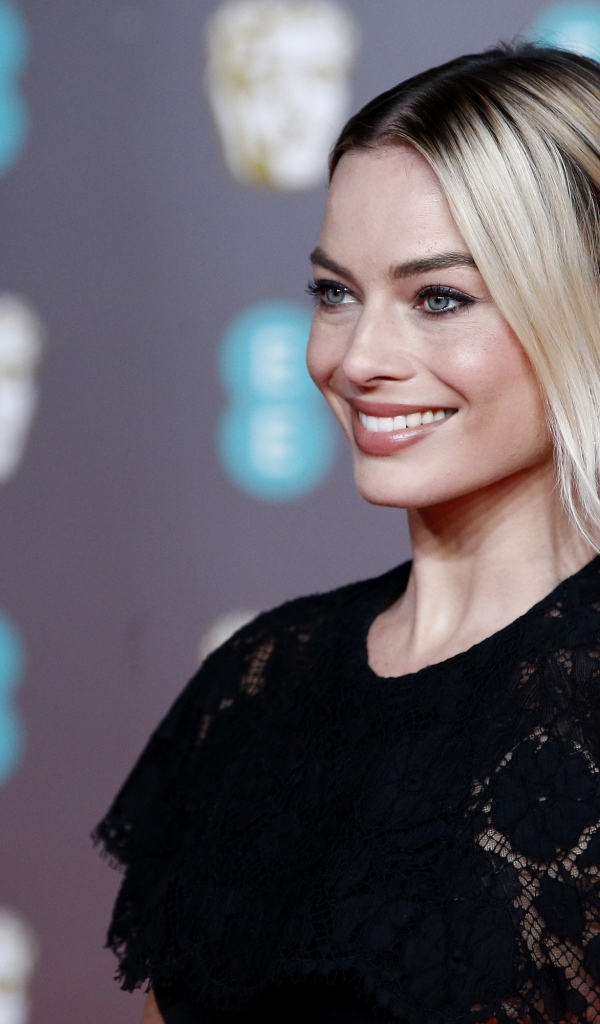 Улыбающаяся актриса Марго Робби в черном платье 