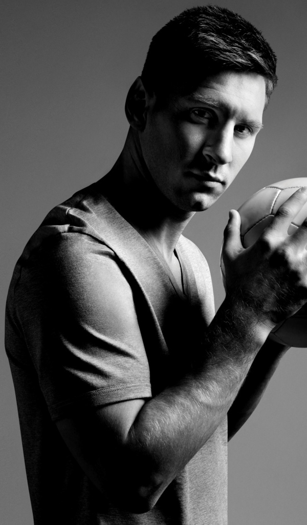 Футболист Лионель Месси с мячом в руках на сером фоне