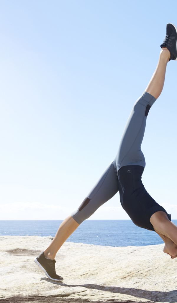 Спортивная девушка делает упражнения на берегу моря 