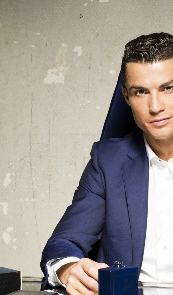 Стильный мужчина, футболист Криштиану Роналду с духами за столом