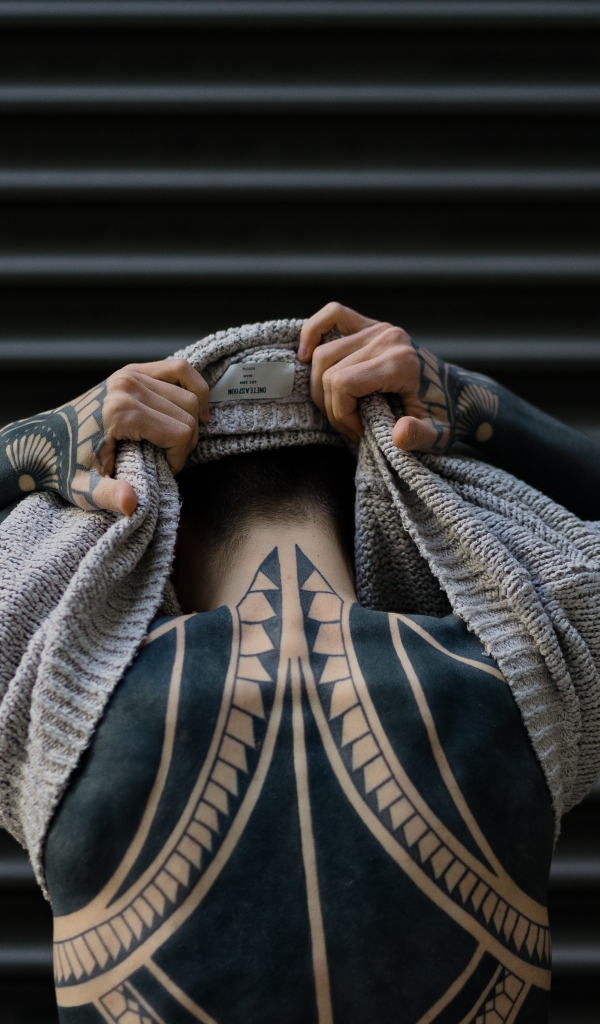 Татуировки на теле мужчины в свитере