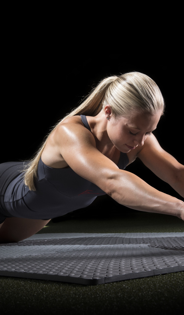 Девушка занимается фитнесом с колесом