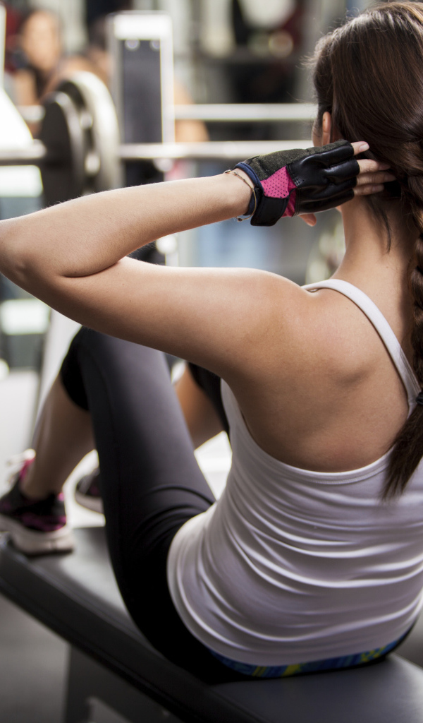 Девушка качает пресс в спортзале 