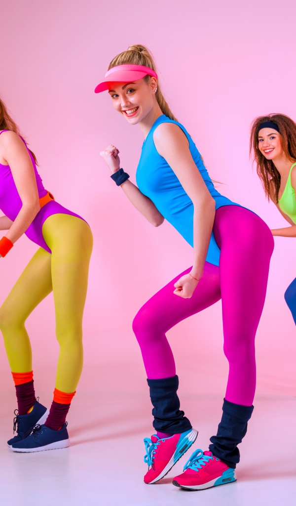 Три девушки занимаются фитнесом на розовом фоне