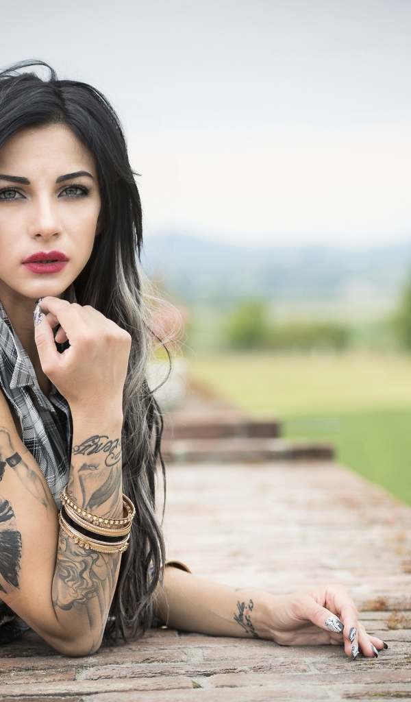 Молодая девушка брюнетка с татуировками на руках