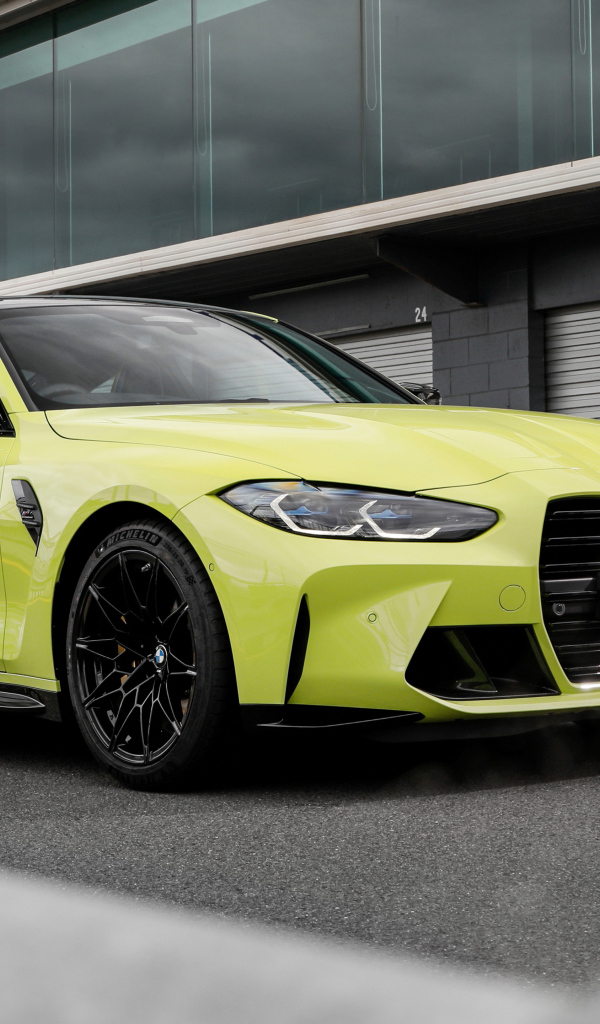 Желтый автомобиль BMW M4 Competition 2021 года у здания