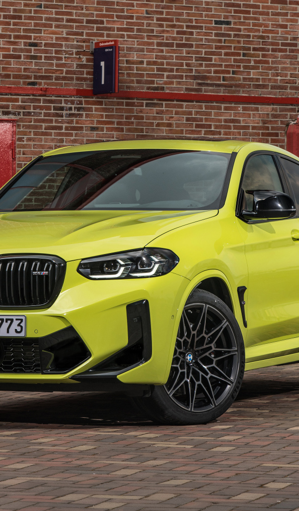 Желтый автомобиль BMW X4 M Competition 2021 года у стены