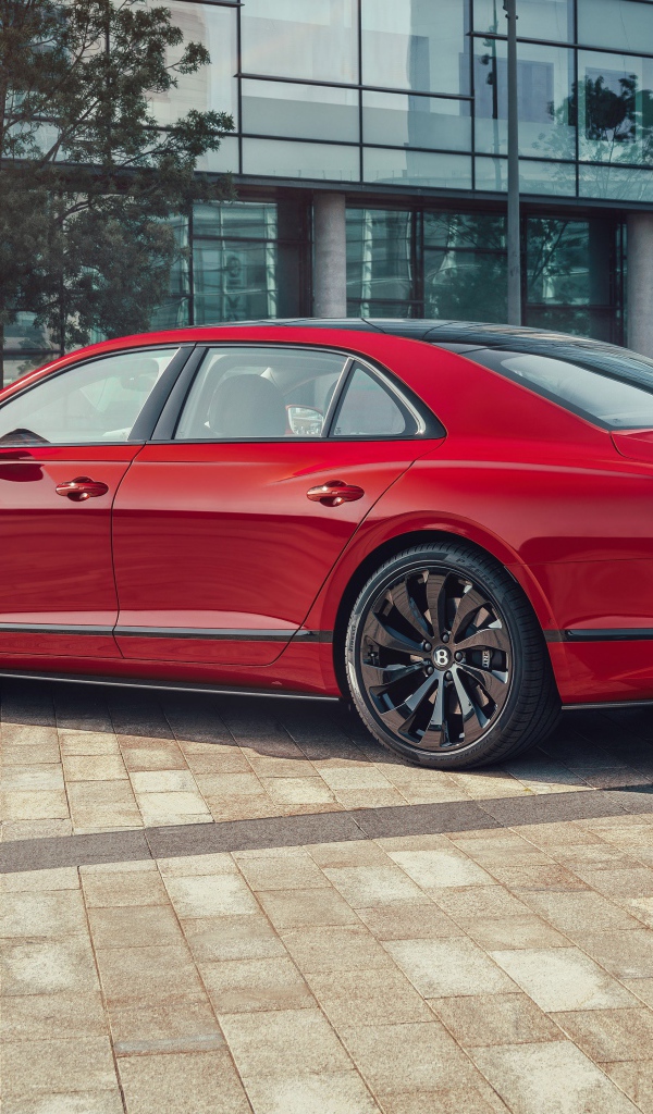 Красный автомобиль Bentley Flying Spur V8 2020 года у здания 