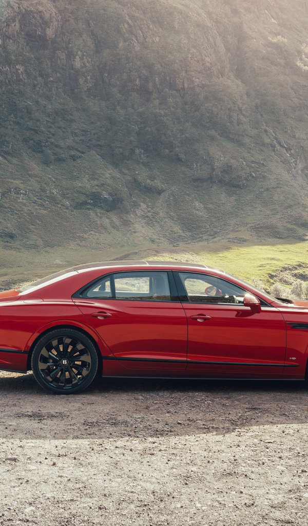Красный автомобиль Bentley Flying Spur V8 2020 года у горы 
