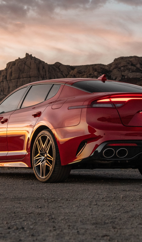 Красный автомобиль Kia Stinger GT, 2022 года в горах вид сзади