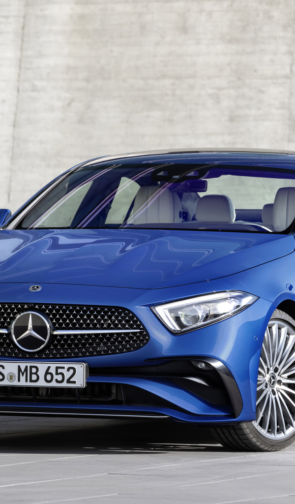 Синий автомобиль Mercedes-Benz CLS 350 AMG Line 2021 года на фоне серой стены
