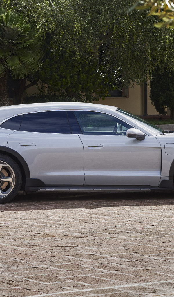 Серебристый автомобиль Porsche Taycan 4S Cross Turismo 2021 года у дома