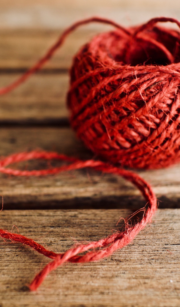 Клубок красной пряжи на деревянном столе 