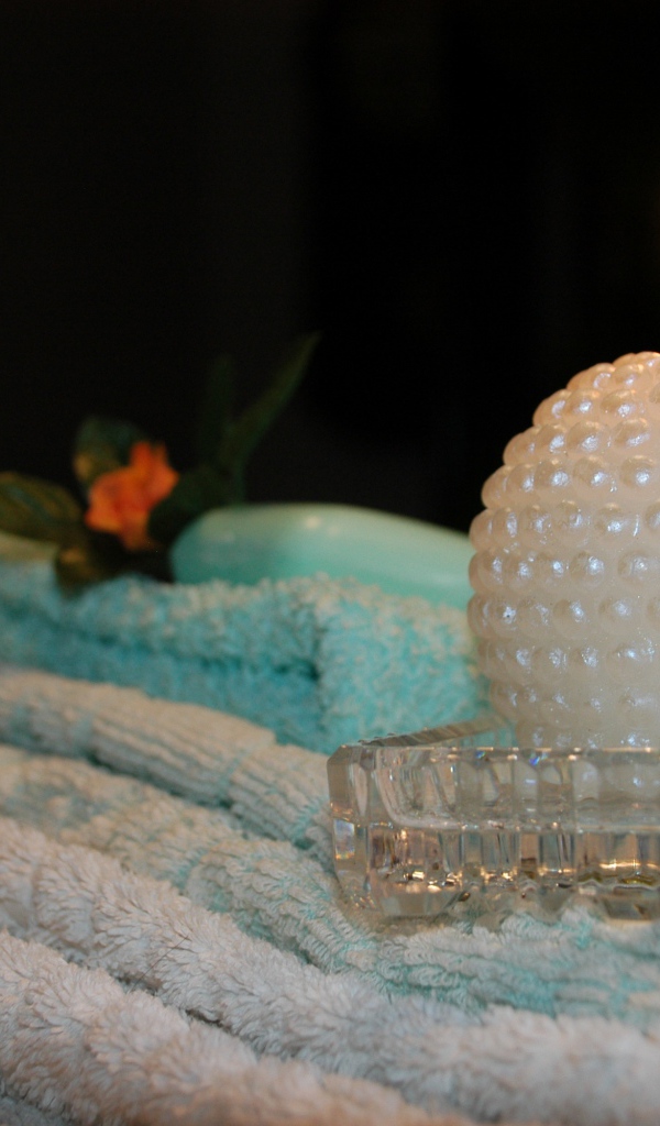 Красивая зажженная свеча с полотенцами