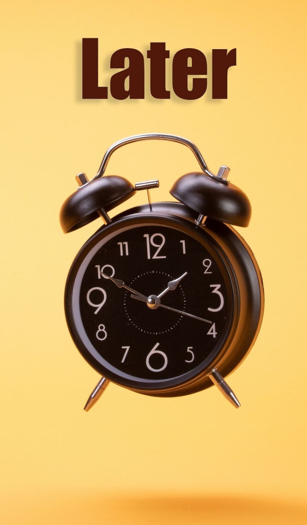 Большой черный будильник на желтом фоне 