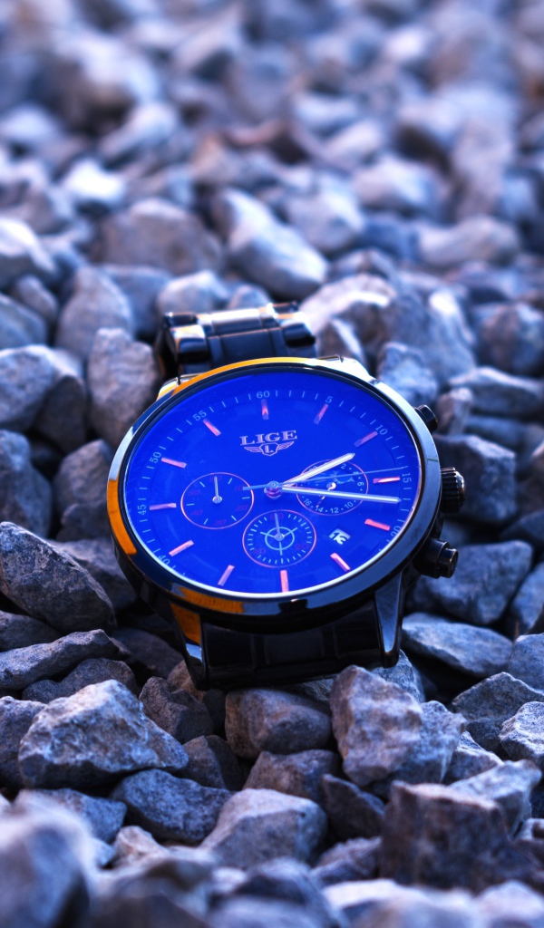 Голубые наручные часы лежат на камнях