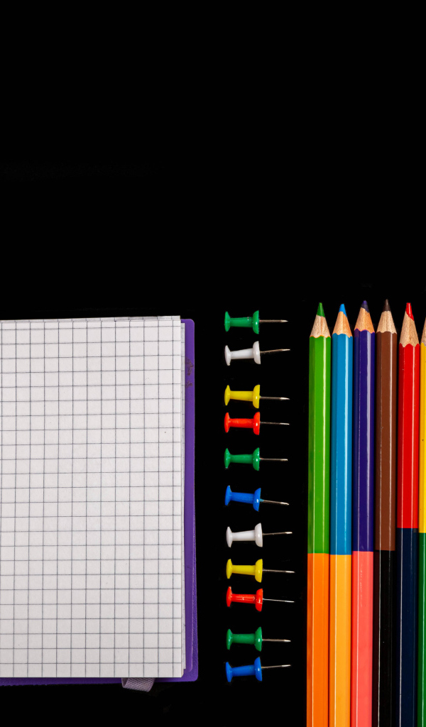 Фломастеры, карандаши, тетрадь и кисточки на черном фоне 