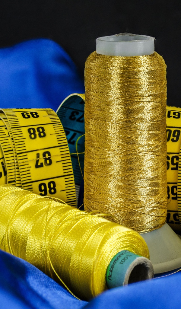 Золотые нитки и сантиметр на голубой ткани 