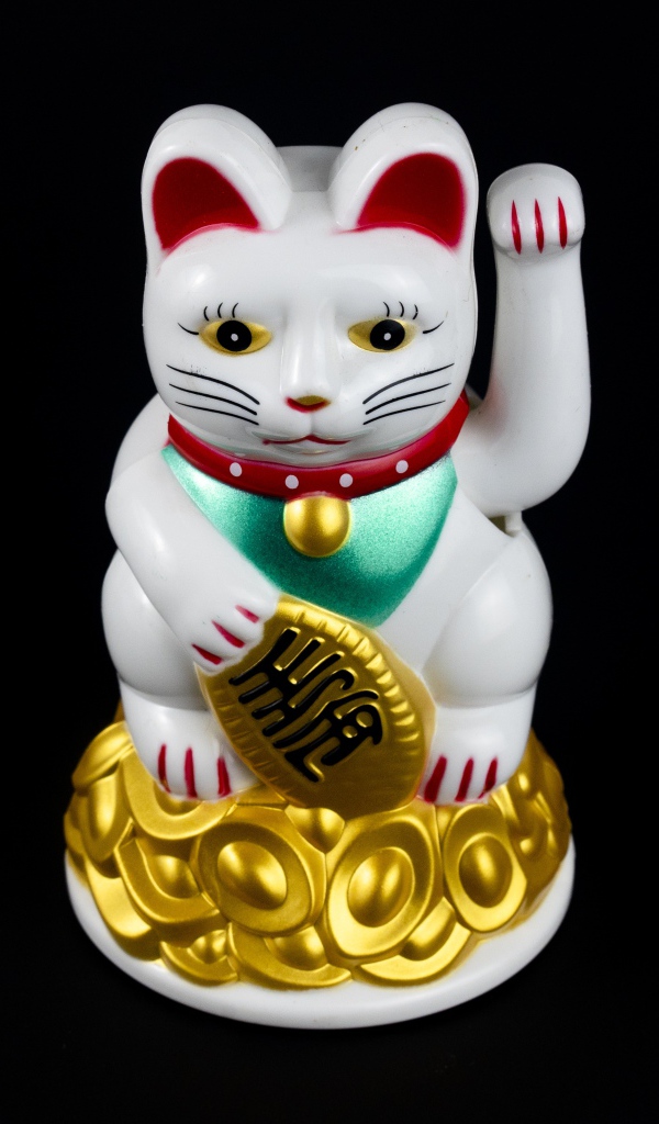 Японская фигурка манэки-нэко кошка на черном фоне