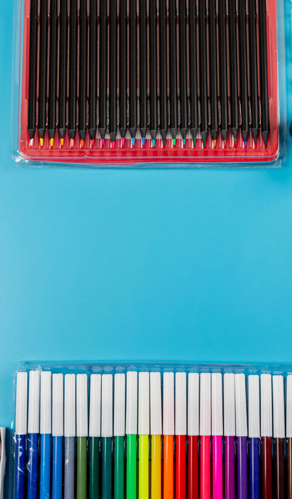 Много разноцветных канцелярских предметов на голубом фоне 