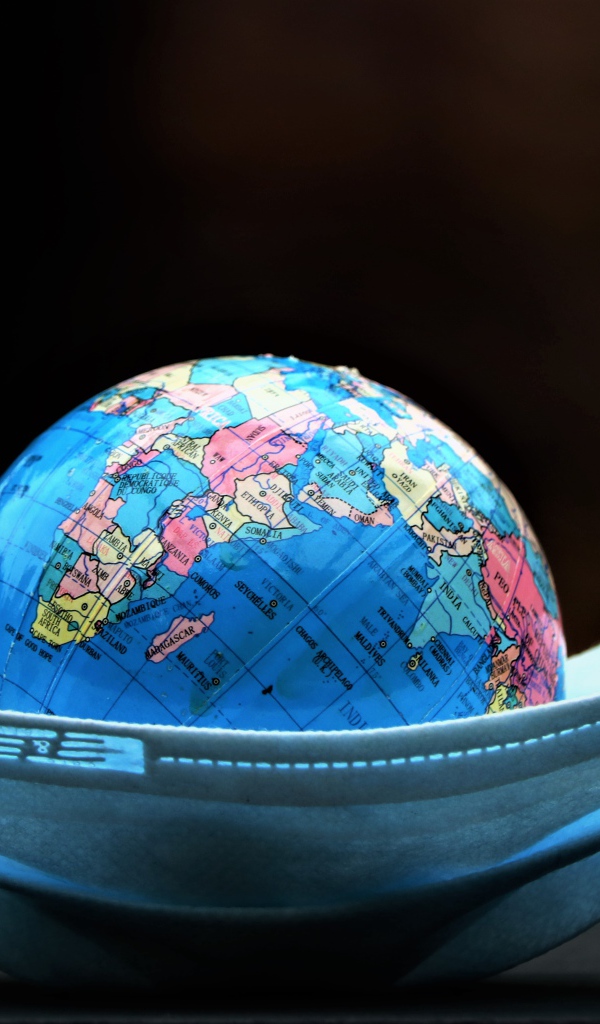 Медицинская маска и глобус на черном фоне