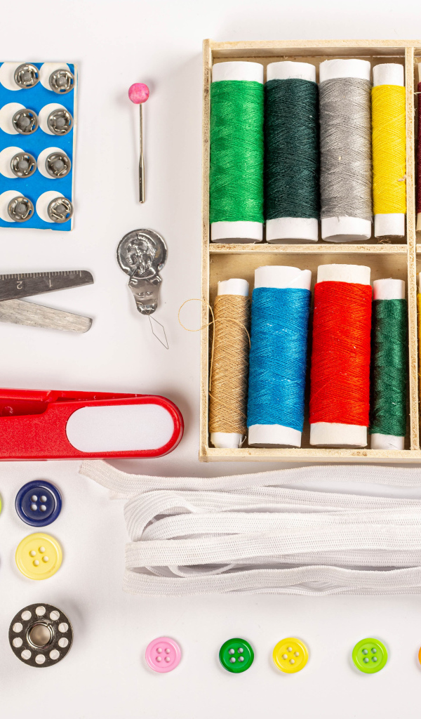 Разноцветые нитки и предметы для шитья на белом фоне 