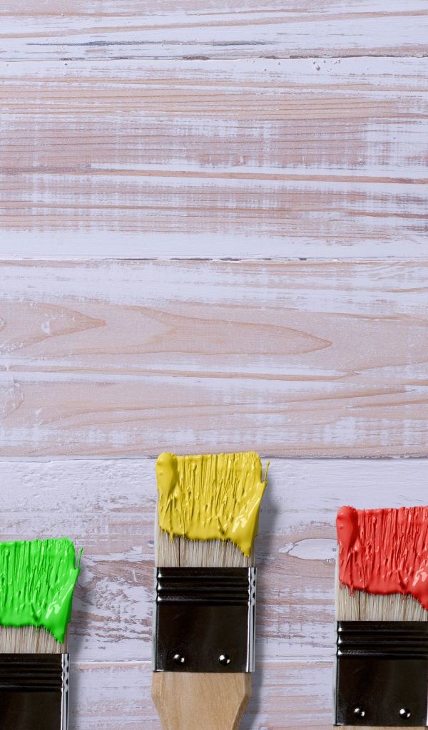 Кисточки в краске на деревянном фоне