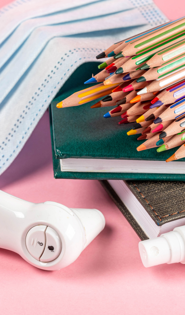 Карандаши, градусник, маска и блокнот на розовом фоне 