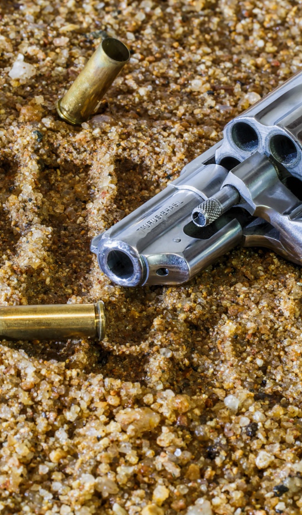 Револьвер с гильзами лежат на песке