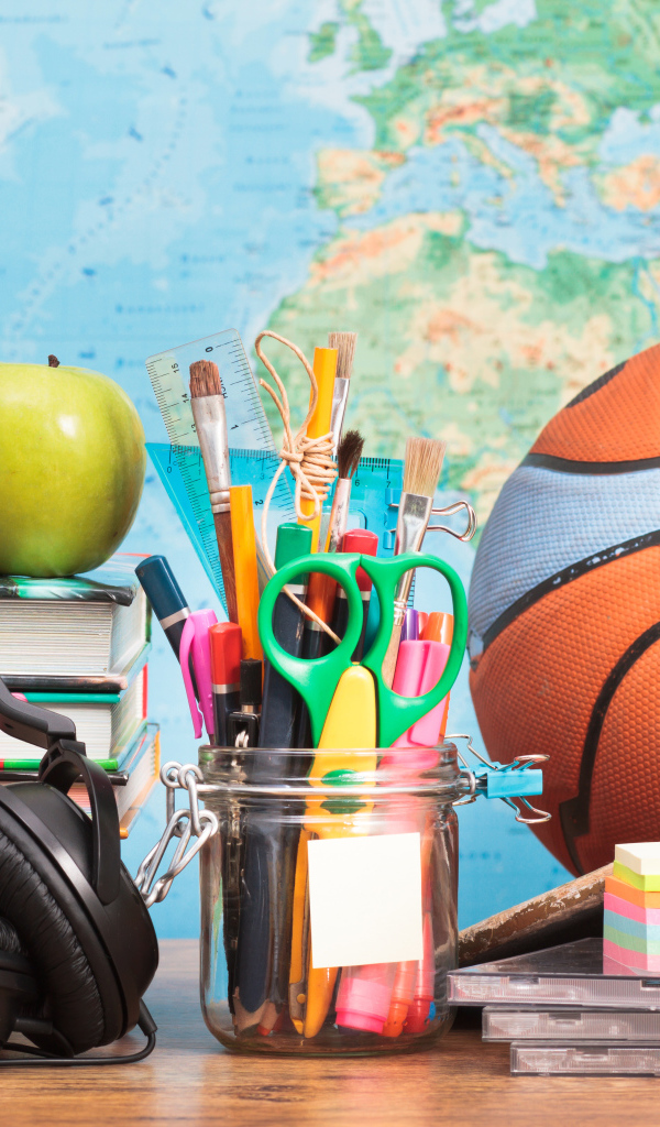 Школьные принадлежности на столе с наушниками и мячом 