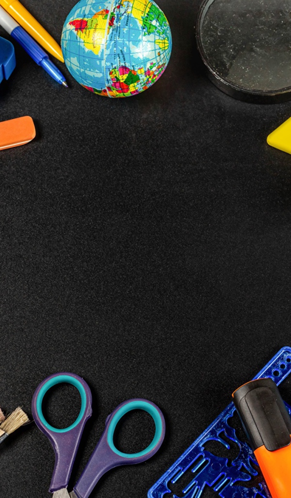 Канцелярские предметы, игрушки и маска на черном столе 